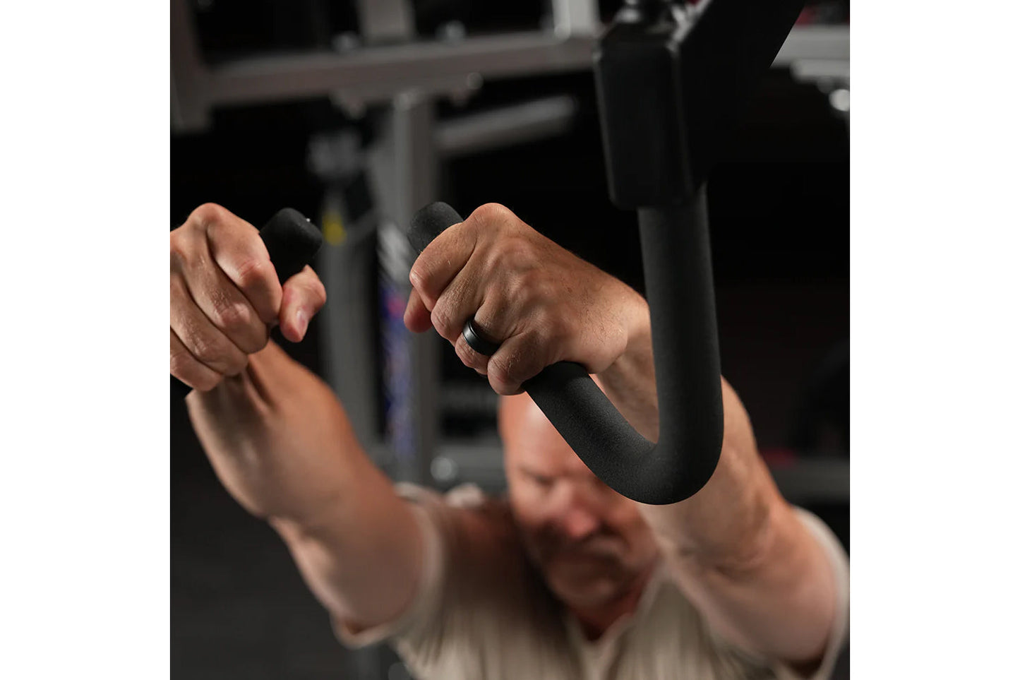 Person performing high row exercise with black handles on Hammer Strength machine in gym