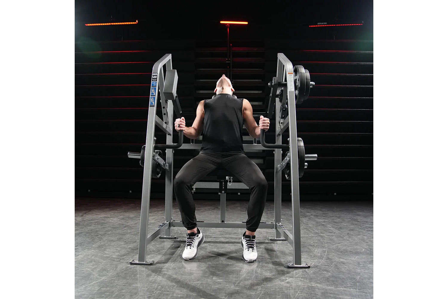 Male athlete using Hammer Strength plate-loaded 4-way neck machine in gym with neon-lit background