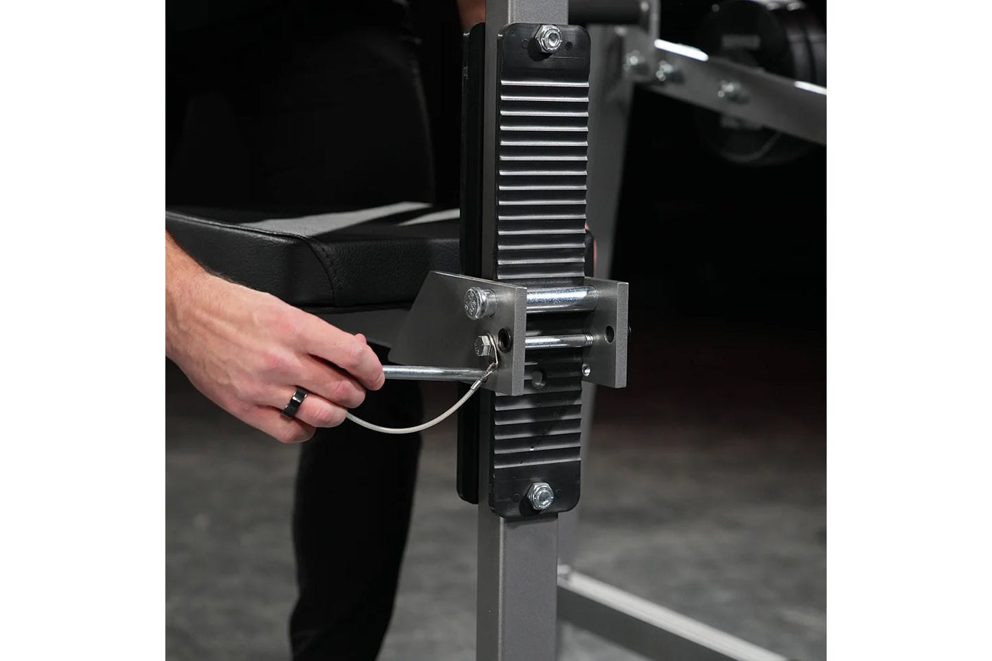 Man using black and chrome plate-loaded neck exercise machine with horizontal slatted backrest in gym setting