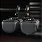 Pair of black leather neck exercise machine attachments with silver hardware and adjustable headrest pads, flat lay on dark b