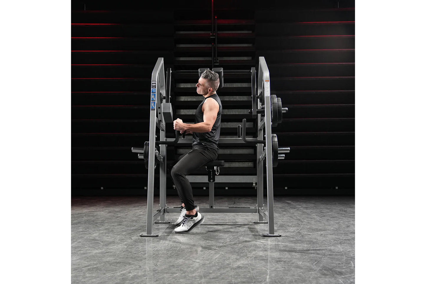 Man using silver Hammer Strength plate-loaded neck machine in gym setting, demonstrating lateral neck exercise movement