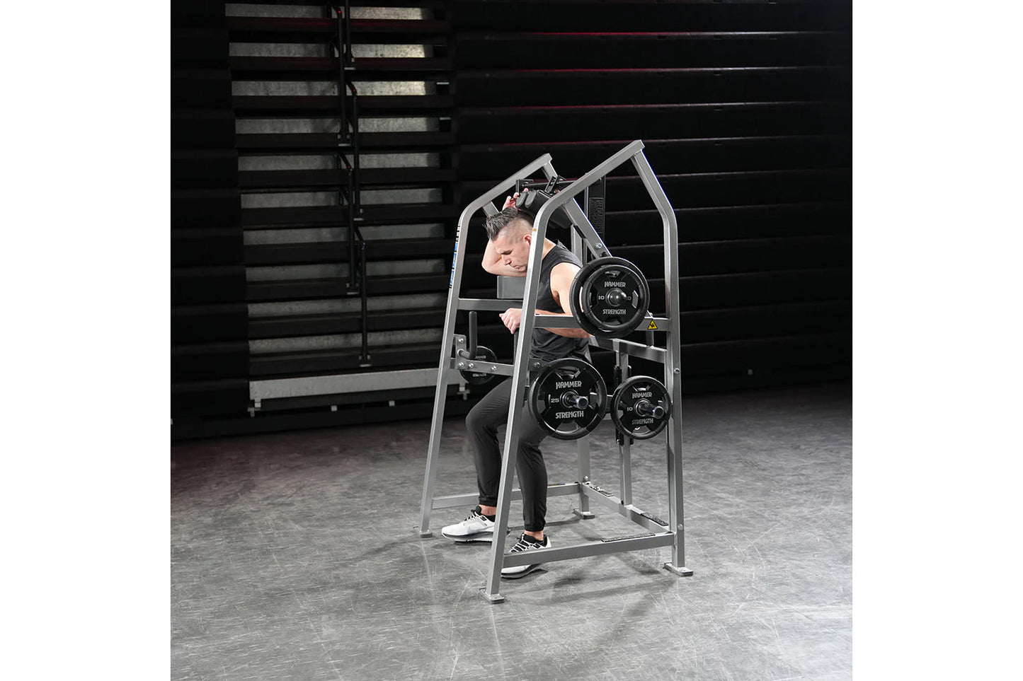 Man using silver Hammer Strength plate-loaded 4-way neck machine with weight plates in gym setting