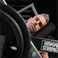Man using black Hammer Strength plate-loaded neck exercise machine, tilting head back on padded support