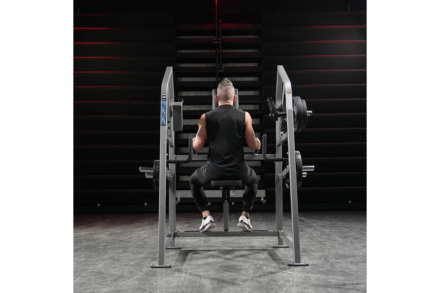 Athlete performing exercise on Hammer Strength plate-loaded neck machine with weighted plates in gym setting