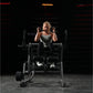Woman performing abdominal crunch on Hammer Strength plate-loaded machine, wearing gray tank top and black leggings in gym se