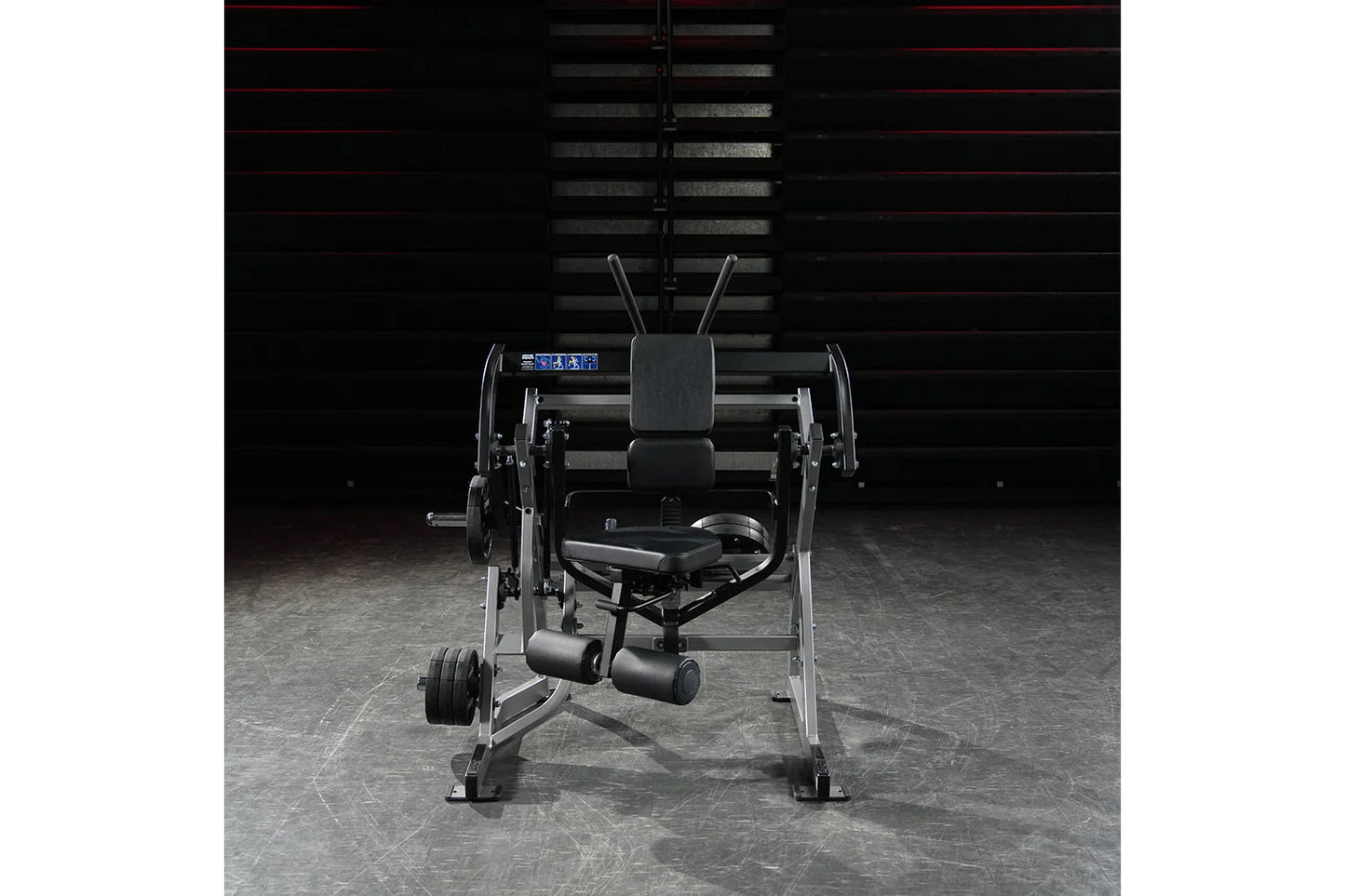 Hammer Strength black plate-loaded abdominal oblique crunch machine with dual handles and foot pedals, front view on gray flo