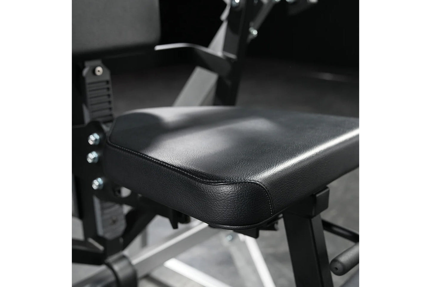 Black leather padded seat with chrome studs on Hammer Strength abdominal machine, detail view