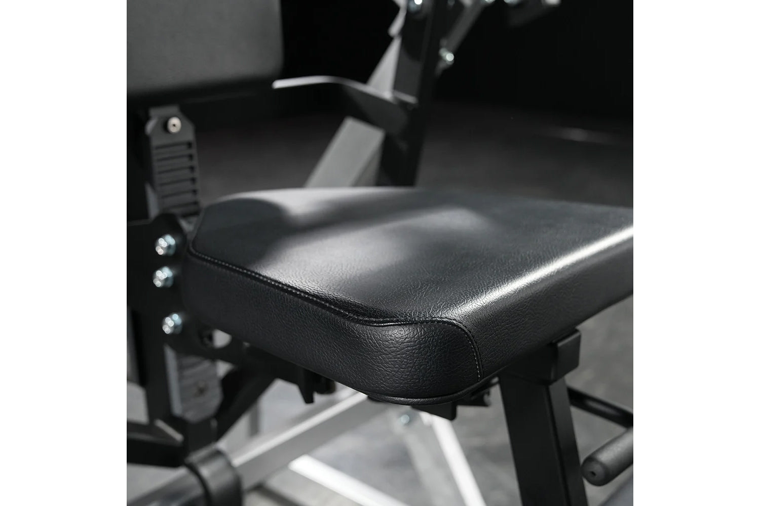 Black leather padded seat with chrome studs on Hammer Strength abdominal machine, detail view