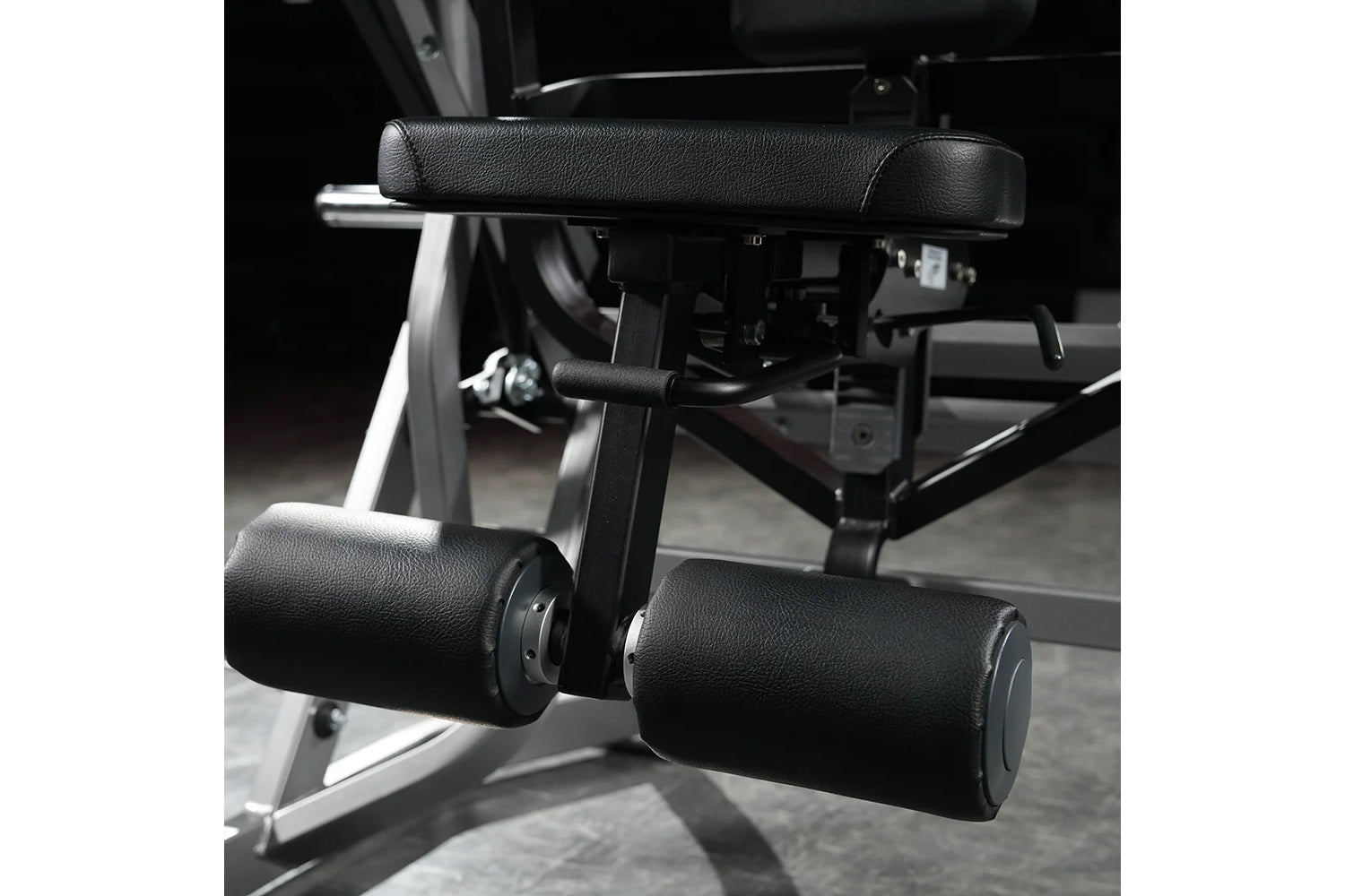 Black and silver plate-loaded abdominal oblique crunch machine with padded black leather handles and foot platform in gym set