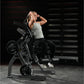 Woman using black Hammer Strength plate-loaded abdominal oblique crunch machine in gym setting, wearing gray tank top and bla