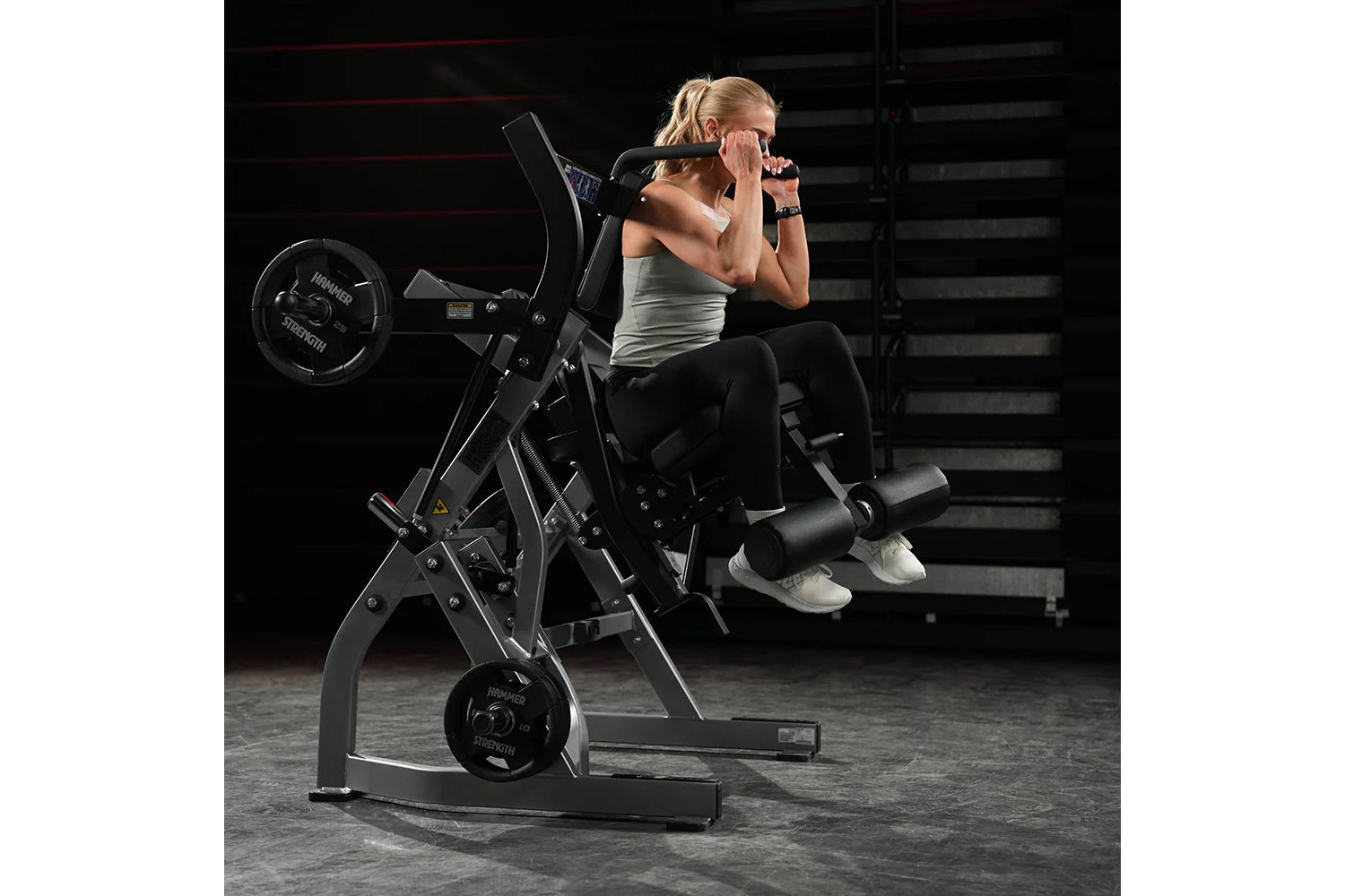 Woman using black Hammer Strength plate-loaded abdominal oblique crunch machine in gym setting