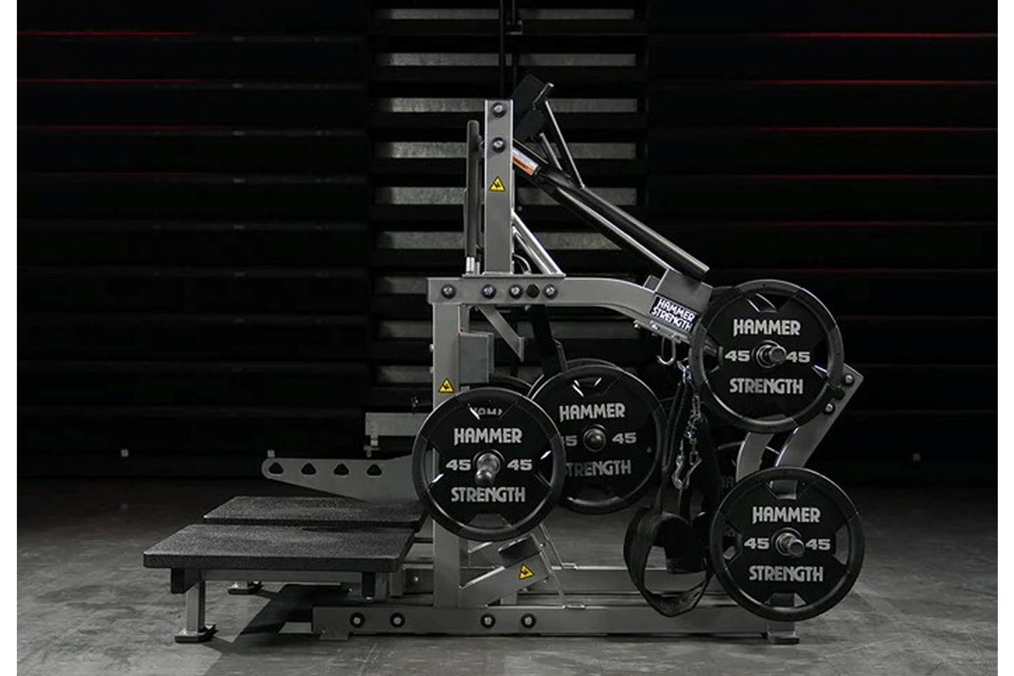 Hammer Strength plate-loaded belt squat machine with gray steel frame, black weight plates labeled 45, and integrated bench o