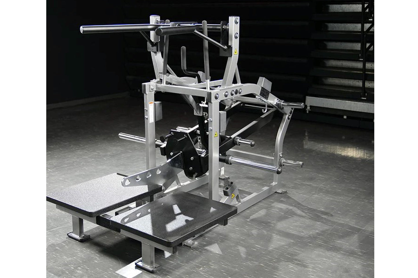 Hammer Strength plate-loaded belt squat machine with silver aluminum frame, black foot platform, and horizontal bar, on concr
