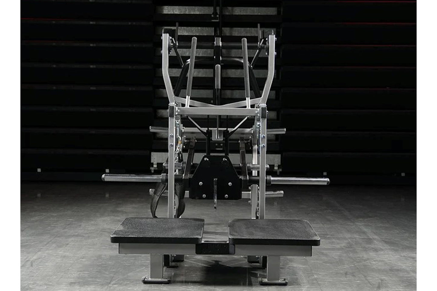 Hammer Strength plate-loaded belt squat machine with silver frame, dual foot platforms, and weight plate pegs, shown in comme