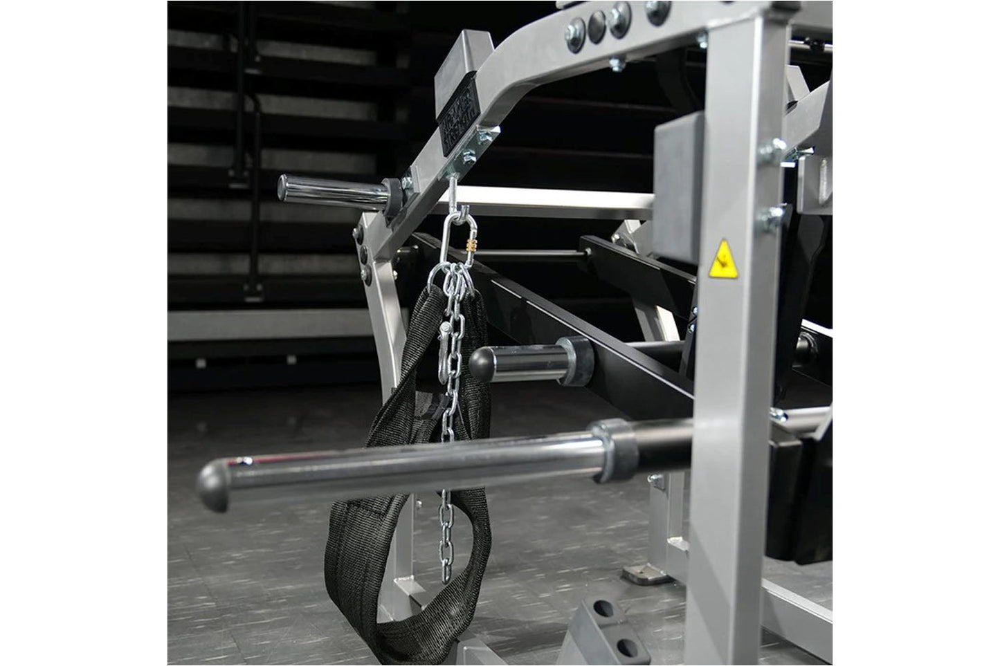 Hammer Strength plate-loaded belt squat machine with gray frame, black straps, and chain attachment in gym setting