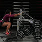 Woman in burgundy top performing leg exercise on Hammer Strength plate-loaded belt squat machine with weight plates in gym se
