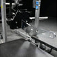 Hammer Strength plate-loaded belt squat machine with silver frame and black seat, featuring weight plate pegs and control pan