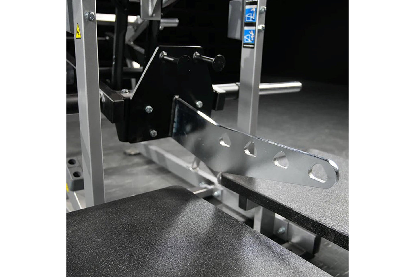 Hammer Strength plate-loaded belt squat machine with silver frame and black seat, featuring weight plate pegs and control pan