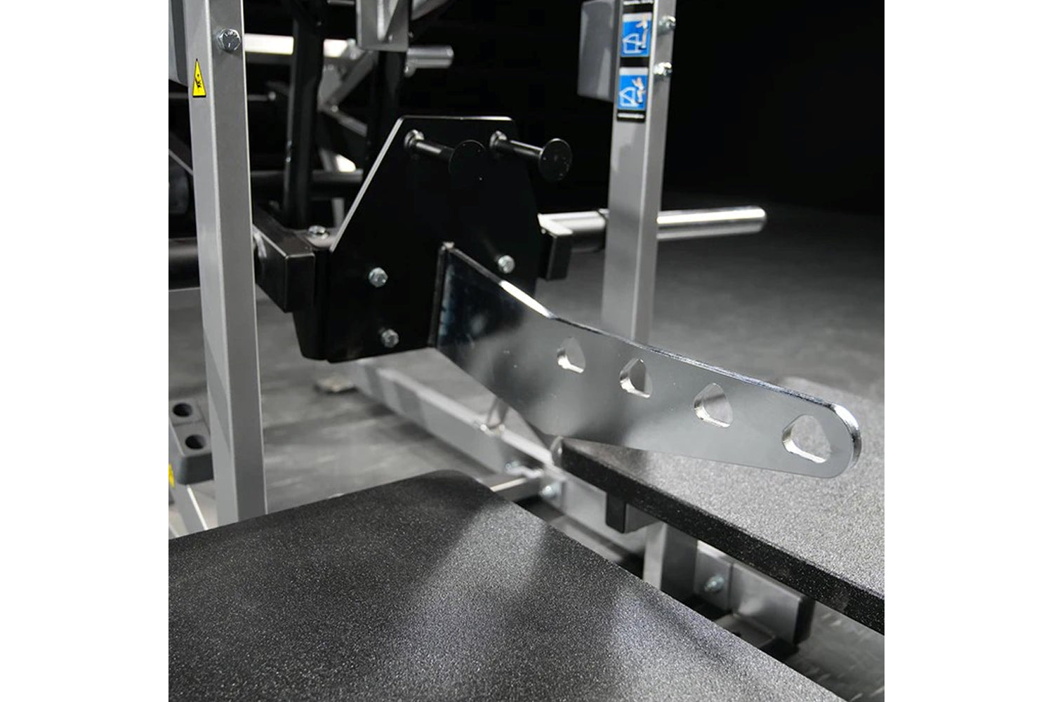 Hammer Strength plate-loaded belt squat machine with silver frame and black seat, featuring weight plate pegs and control pan