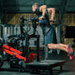Man using Hammer Strength plate-loaded belt squat machine in gym, wearing dark tank top and red sneakers