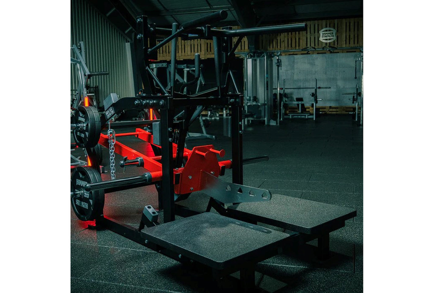 Hammer Strength plate-loaded belt squat machine with red and black frame in gym facility setting