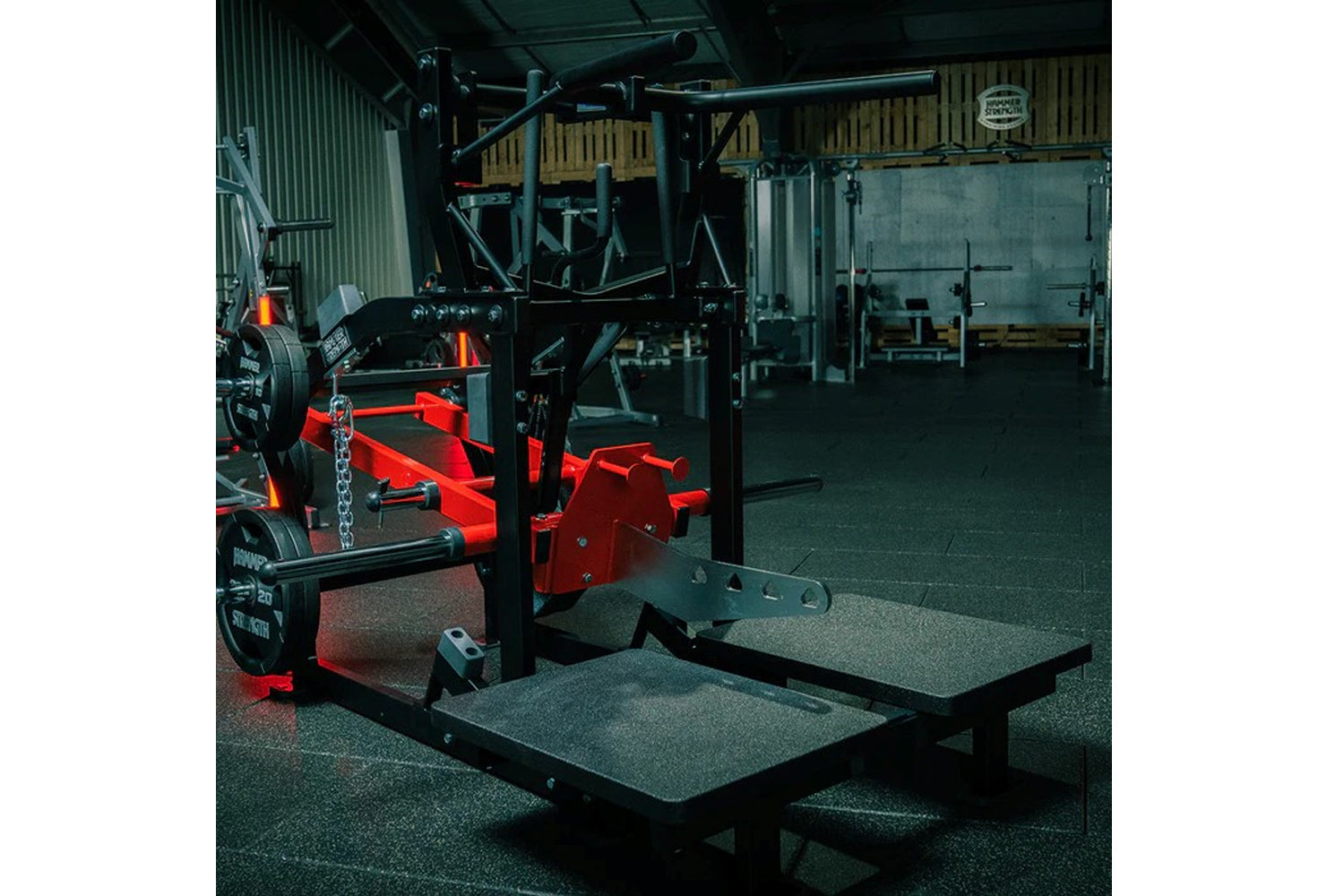 Hammer Strength plate-loaded belt squat machine with red and black frame in gym facility setting
