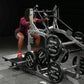Person in burgundy top using Hammer Strength plate-loaded belt squat machine with black weight plates, on gray floor