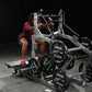 Woman in burgundy shirt using silver and black Hammer Strength plate-loaded belt squat machine with weight plates loaded