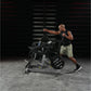Man wearing black sleeveless tank and beige shorts using Hammer Strength plate-loaded combo twist machine in gym setting