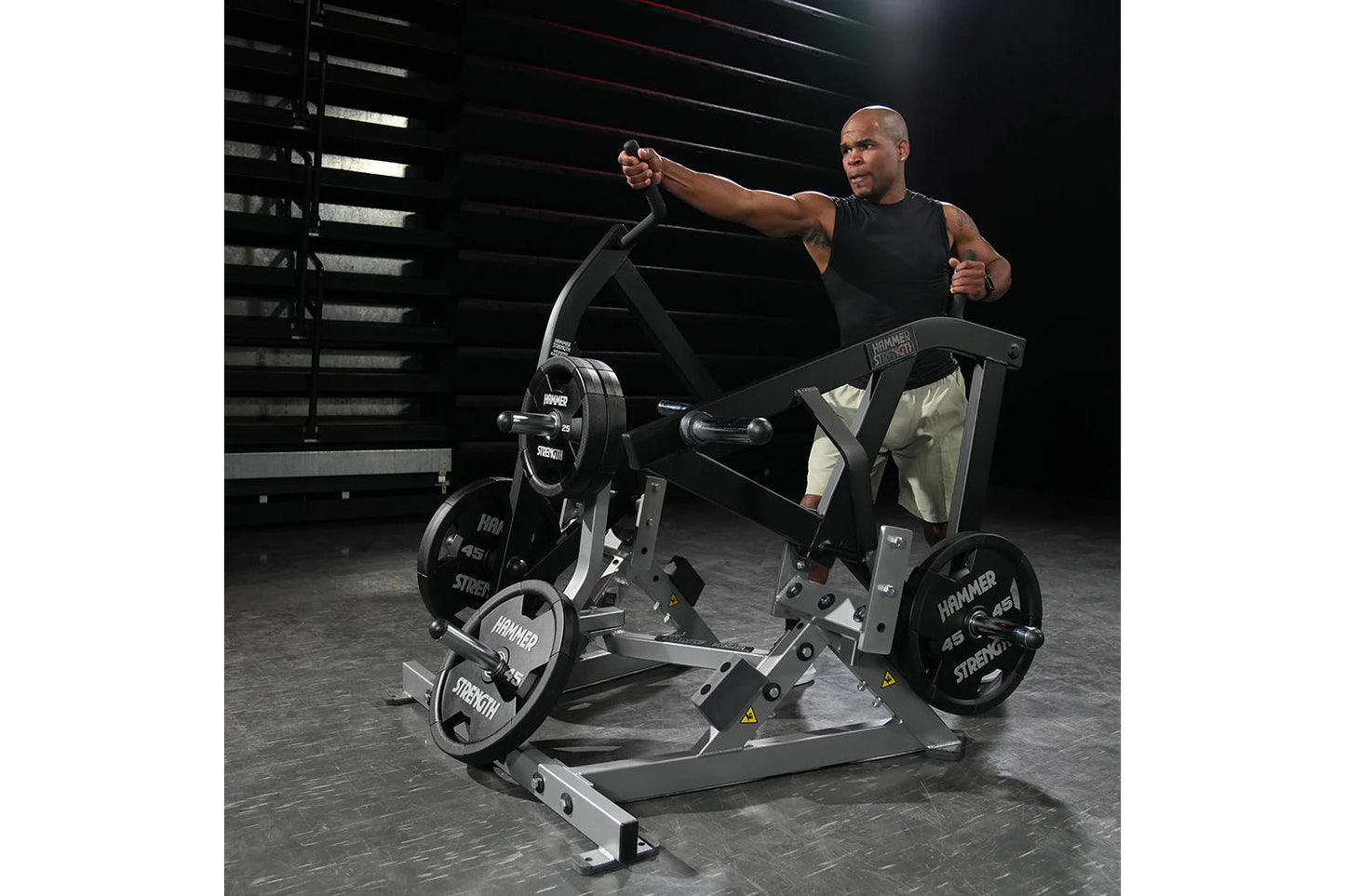 Man in black sleeveless shirt using black and silver Hammer Strength plate-loaded combo twist exercise machine in gym setting