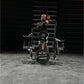 Man in black sleeveless shirt performing squat on Hammer Strength plate-loaded machine with 45-pound weights loaded, industri