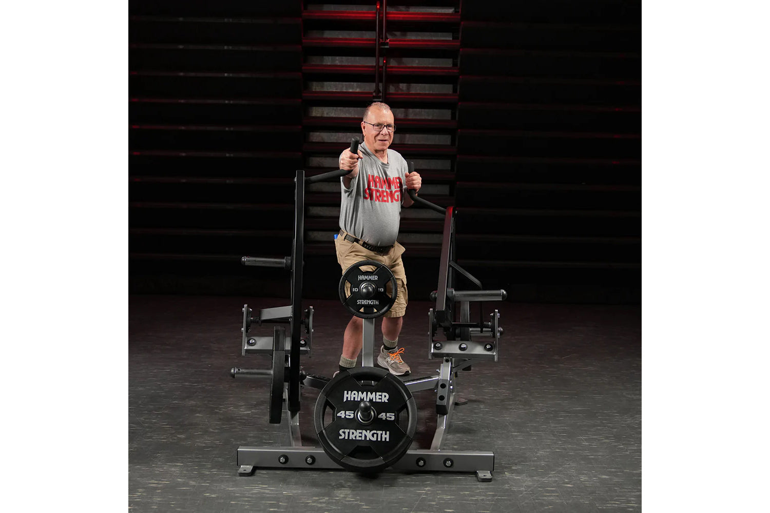 Man wearing gray t-shirt and tan shorts performing a twist exercise on black Hammer Strength plate-loaded machine in gym sett