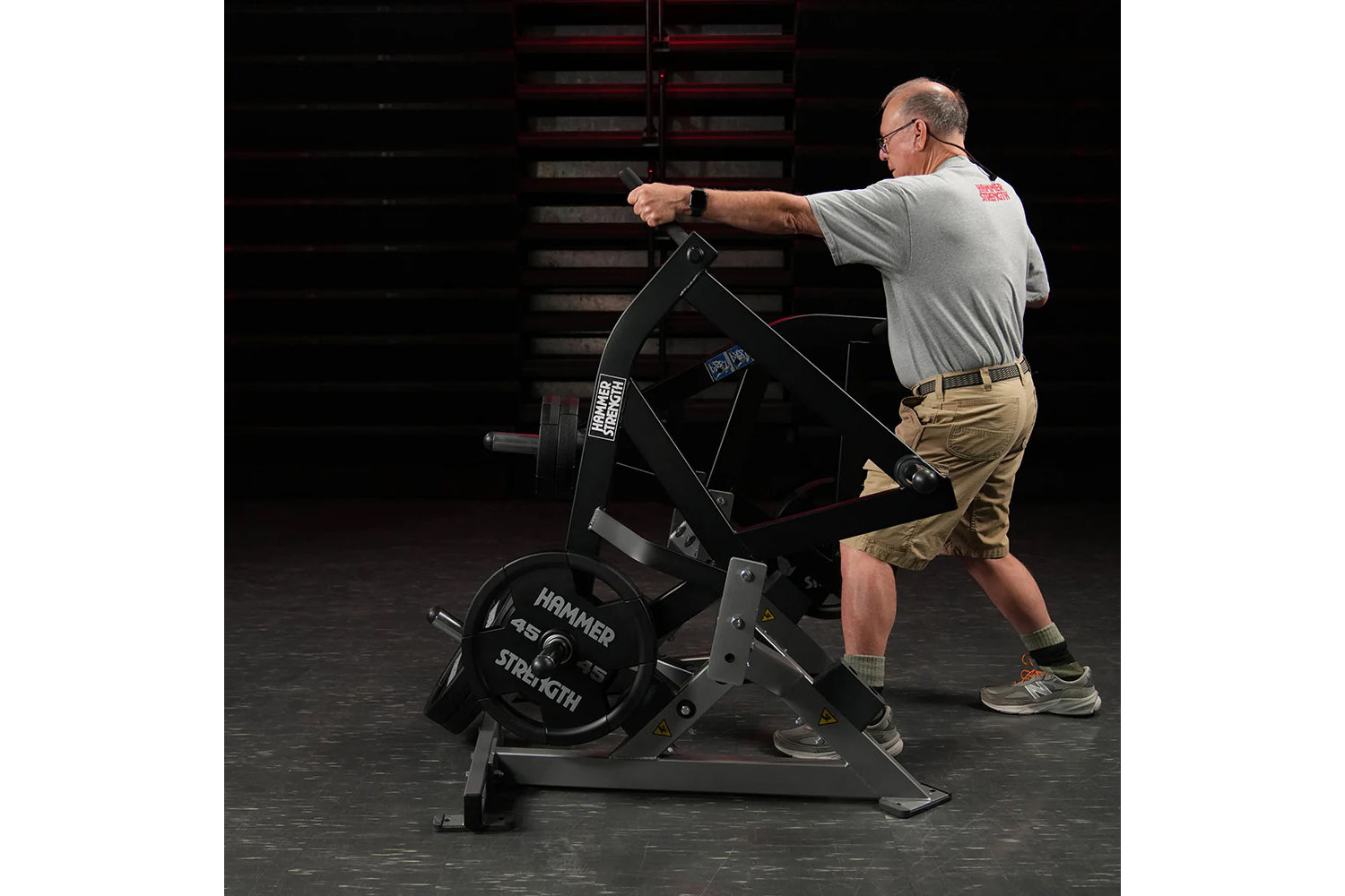 Man using black Hammer Strength plate-loaded combo twist machine in gym setting, wearing gray shirt and khaki shorts