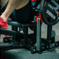 Person wearing red shoes using black Hammer Strength plate-loaded glute drive machine in gym setting