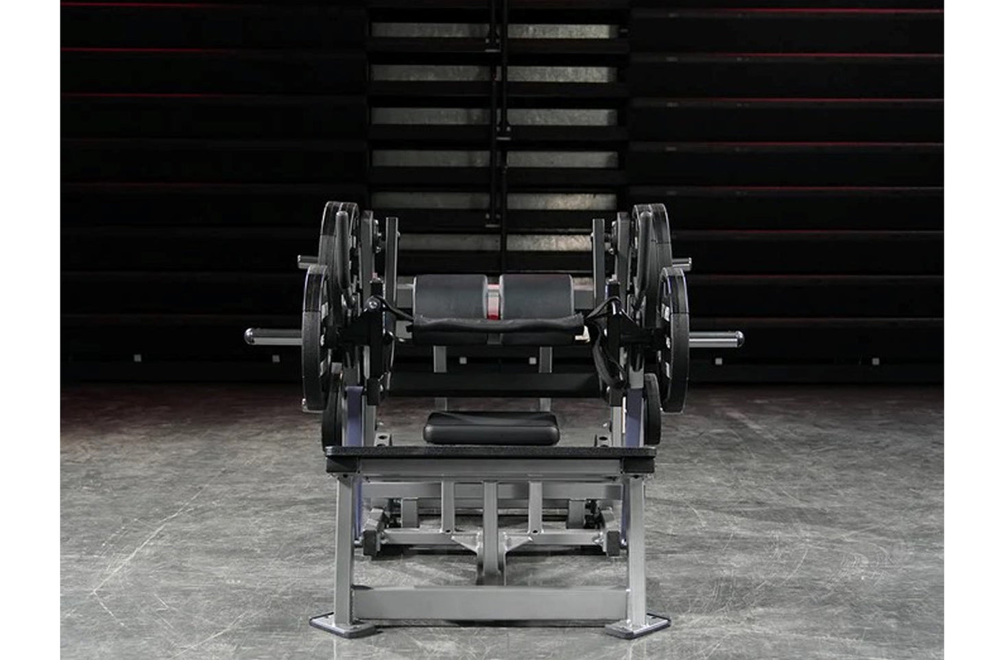 Hammer Strength plate-loaded glute drive machine with black weight plates and gray metal frame in gym setting