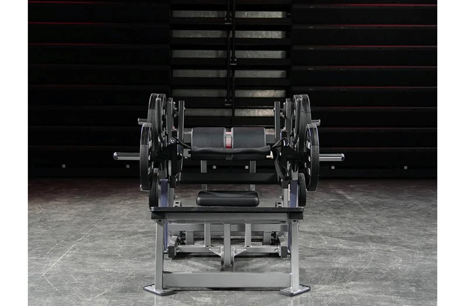 Hammer Strength plate-loaded glute drive machine with black weight plates and gray metal frame in gym setting