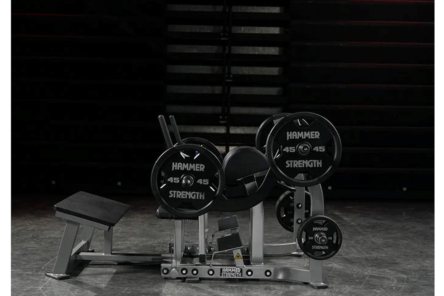 Hammer Strength plate-loaded glute drive machine with black weight plates and metal frame in gym setting