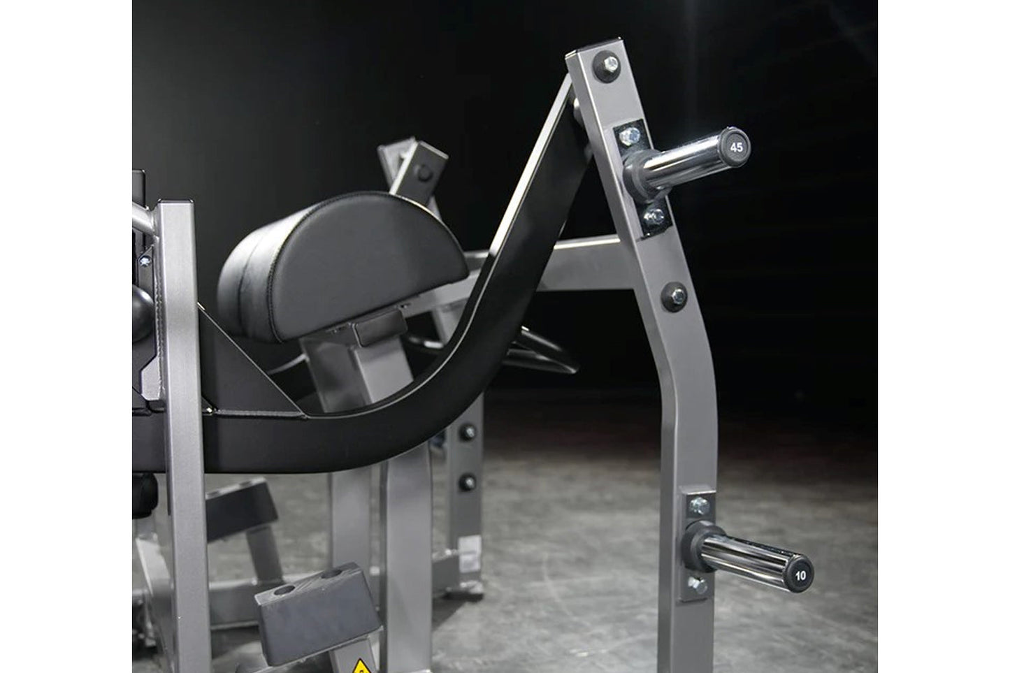 Hammer Strength plate-loaded glute drive machine with black padded seat, chrome handles, and silver steel frame on dark backg