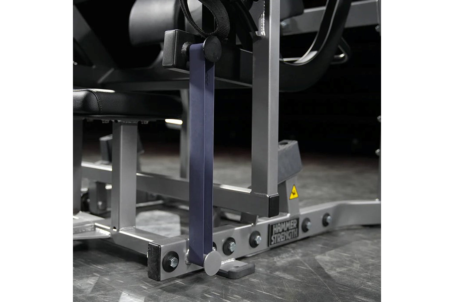 Hammer Strength plate-loaded glute drive machine with blue vertical supports and gray metal frame on gym floor