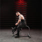 Man seated on weight bench performing dumbbell curl exercise in industrial gym setting with red neon lighting