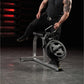 Man in black athletic wear seated on Hammer Strength plate-loaded leg press machine in gym setting with red neon lighting
