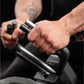 Person gripping black and silver plate-loaded gripper with cylindrical handles, demonstrating exercise equipment on dark back