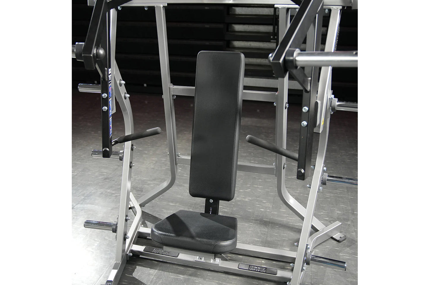 Hammer Strength plate-loaded iso-lateral bench press machine with black padded seat and backrest, silver metal frame, in gym 