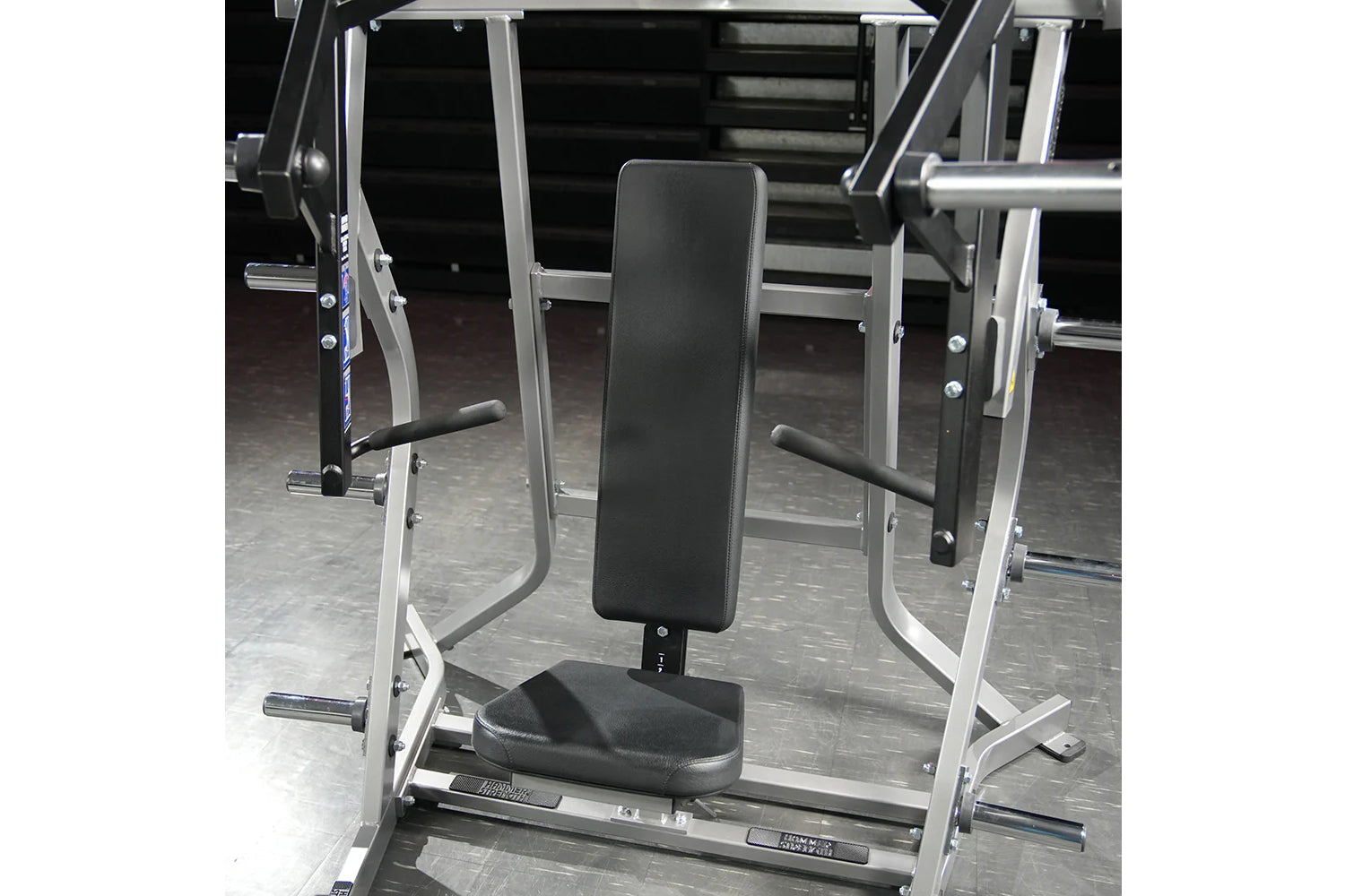 Hammer Strength plate-loaded iso-lateral bench press machine with black padded seat and backrest, silver metal frame, in gym 