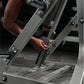 Person using gray Hammer Strength plate-loaded iso-lateral bench press machine with chrome handles and foot platform