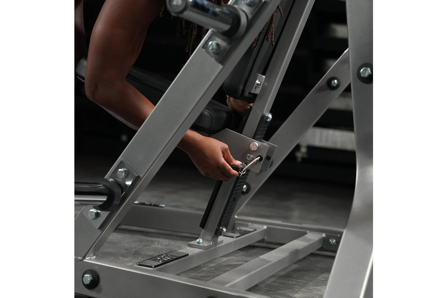 Person using gray Hammer Strength plate-loaded iso-lateral bench press machine with chrome handles and foot platform