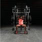 Woman in coral tank top and black shorts performing chest press on silver and black plate-loaded bench press machine in gym