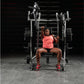 Athlete wearing coral tank top and black shorts performing bench press on Hammer Strength plate-loaded machine in gym setting