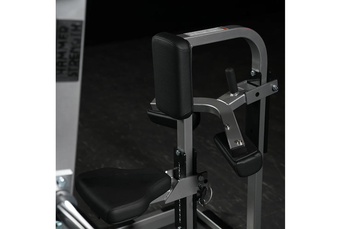 Hammer Strength plate-loaded chest/back machine with black padded seat and backrest, gray metal frame, against black backgrou