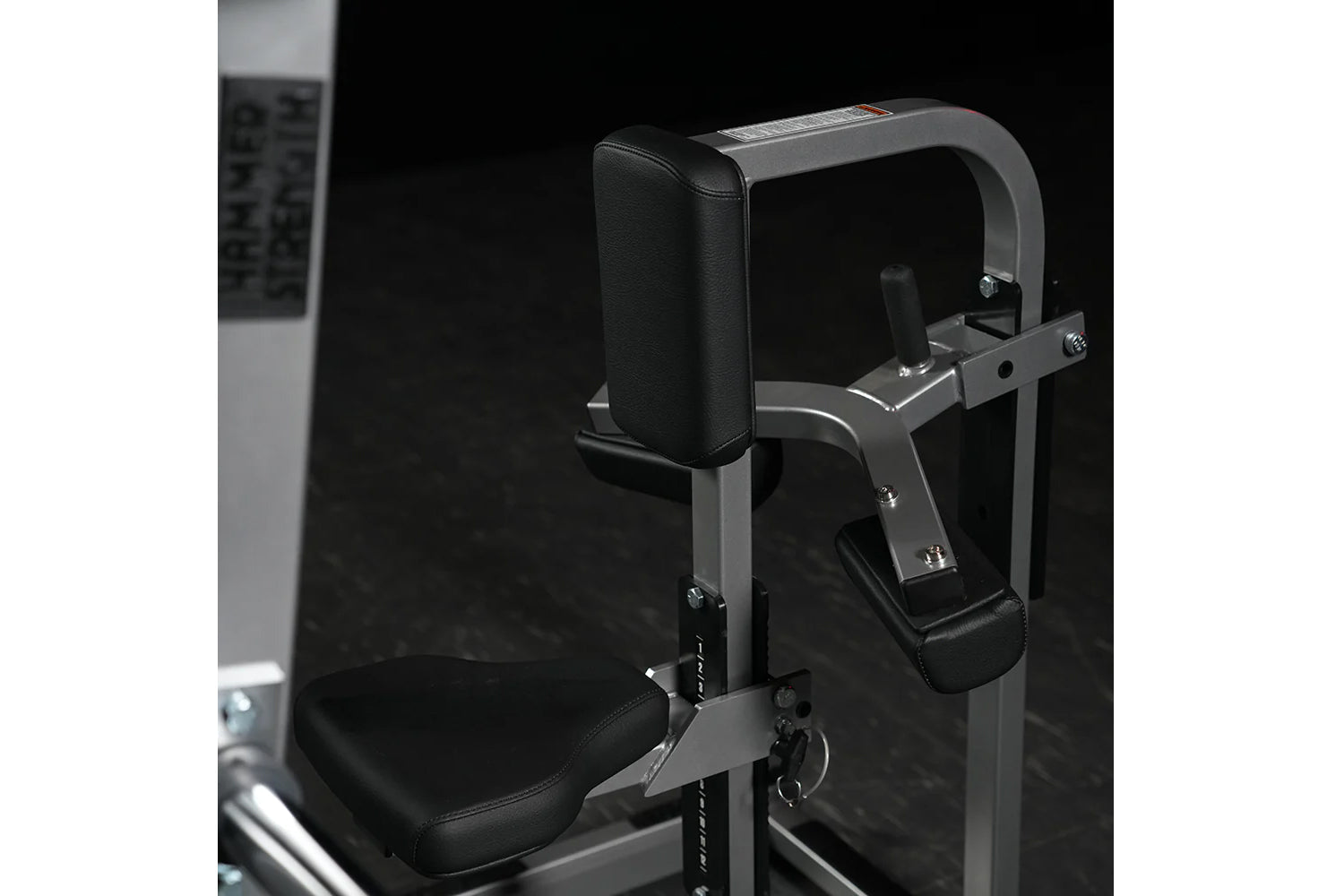 Hammer Strength plate-loaded chest/back machine with black padded seat and backrest, gray metal frame, against black backgrou